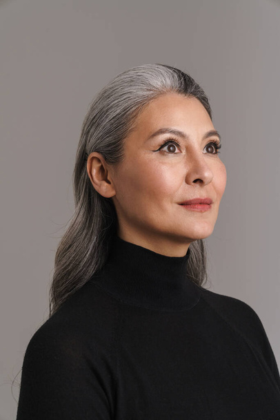 Mature woman with white hair posing and looking aside isolated over grey background - Photo, Image