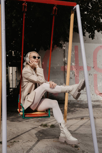 Portrait de femme blonde dans un casque écoutant de la musique avec des lunettes de soleil. Hipster fashion model porter des écouteurs sans fil élégants profiter d'écouter une nouvelle musique cool. - Photo, image