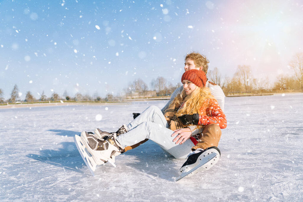 Szerető pár meleg pulóverben, jól érzik magukat a jégen. Nő és férfi korcsolyáznak a szabadban a napsütéses, havas napokon. Aktív dátum a jég arénában télen Szenteste. Romantikus tevékenységek és életmód koncepció. - Fotó, kép