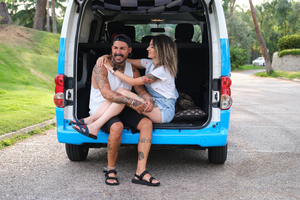 Young tattooed couple smiling and hugging in the back of the van. - Photo, Image