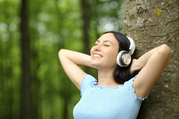 Happy asian woman listening to music wearing headphones in a park - Φωτογραφία, εικόνα
