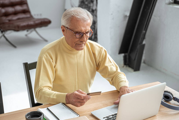 Uomo che utilizza la carta di credito per lo shopping online mentre seduto davanti al computer portatile - Foto, immagini