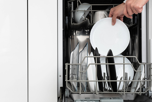 Γυναίκα πλένει πιάτα στο πλυντήριο πιάτων στο σπίτι. Καθαρίστε πιάτα μετά το πλύσιμο μοντέρνα κουζίνα με πλυντήριο πιάτων. Οικιακές δουλειές.  - Φωτογραφία, εικόνα