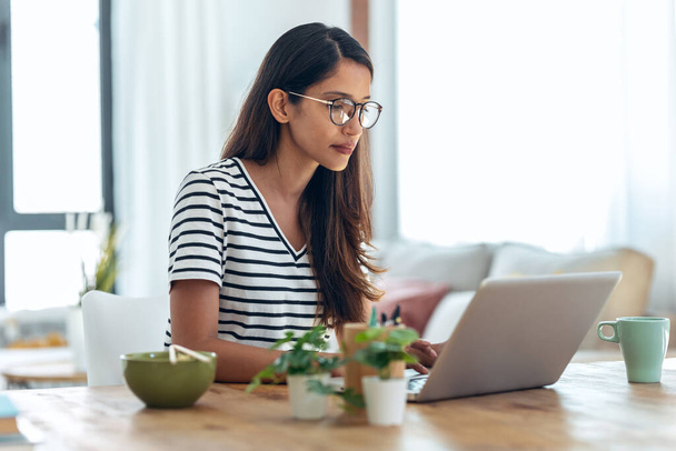 Zdjęcia skoncentrowanej młodej bizneswoman pracującej z laptopem w biurze w domu. - Zdjęcie, obraz