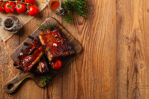 Roasted pork ribs in a bbq sauce. Served on a wooden board. Top view. - Foto, imagen
