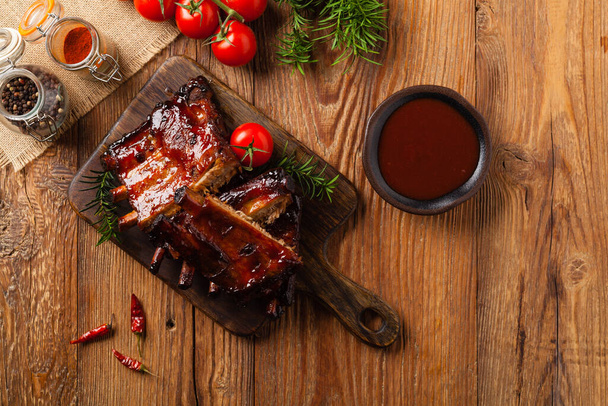 Roasted pork ribs in a bbq sauce. Served on a wooden board. Top view. - Φωτογραφία, εικόνα