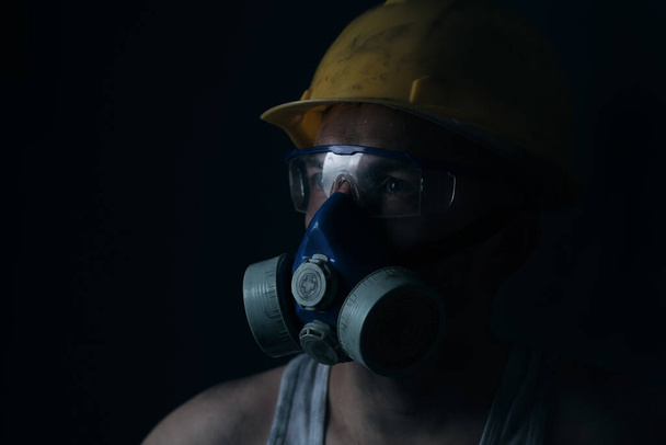 Portrait miner in helmet, respirator and goggles looking at light - Foto, afbeelding