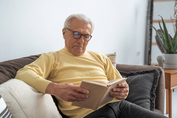 Lovely old man relaxing on couch with pillows at home - Photo, Image