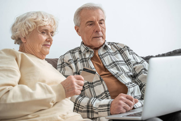 Mature couple making online purchase using credit card and looking with smiled face - Photo, Image