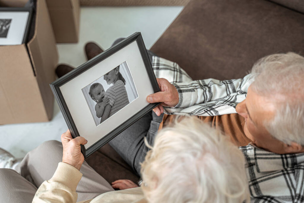 Пожилая пара вспоминает моменты, сидя на диване - Фото, изображение