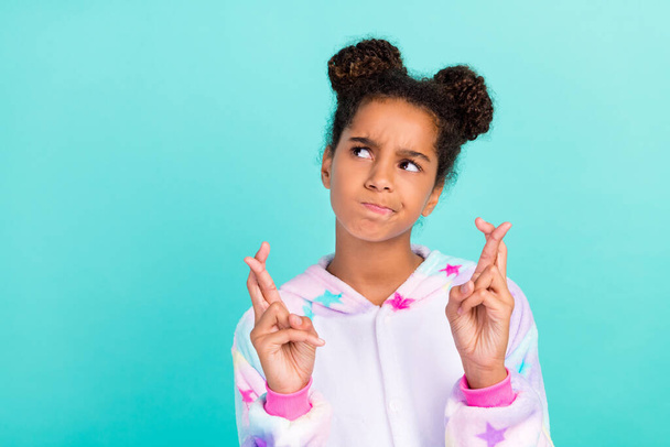 Photo of young african girl worried crossed fingers pleading anticipation look empty space isolated over teal color background - Φωτογραφία, εικόνα