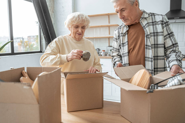 Happy retired senior couple moving into a new home and unpacking boxes - Zdjęcie, obraz
