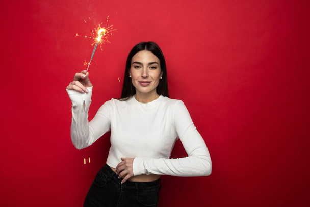 Holiday mood - smiling young woman in a white sweater holding sparklers - Fotografie, Obrázek