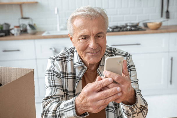 Mature man chatting via smartphone with family and feeling happy - Φωτογραφία, εικόνα