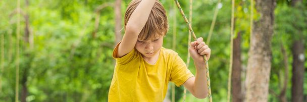 Мальчик в веревочном парке. Активный физический отдых ребенка на свежем воздухе в парке. Обучение для детей BANNER, LONG FORMAT
 - Фото, изображение