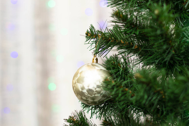 Neujahrsbaum mit grünen Zweigen und Nadeln mit Weihnachtsschmuck auf dem Hintergrund von Girlanden an Silvester. Selektiver Fokus. Nahaufnahme - Foto, Bild