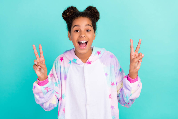 Photo of model african american awake stylish trendy girl v-sign sleepwear childhood pajama nightwear isolated on teal color background - Foto, imagen