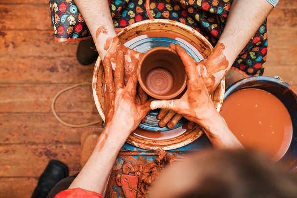 Bir çömlekçi ve bir öğrenci çömlekçi çarkında kilden yapılmış tabaklar yapıyorlar. - Fotoğraf, Görsel