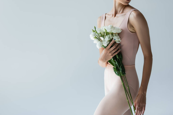 cropped view of young ballerina holding bouquet of flowers isolated on grey - Photo, Image