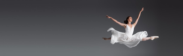 full length of graceful woman in white dress jumping isolated on grey, banner - Φωτογραφία, εικόνα