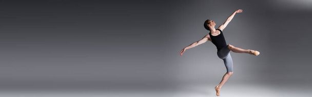 longitud completa de hombre elegante realizando danza de ballet en gris oscuro, bandera - Foto, Imagen