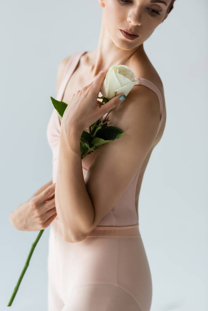partial view of ballerina in bodysuit holding flower isolated on grey - Foto, Imagem