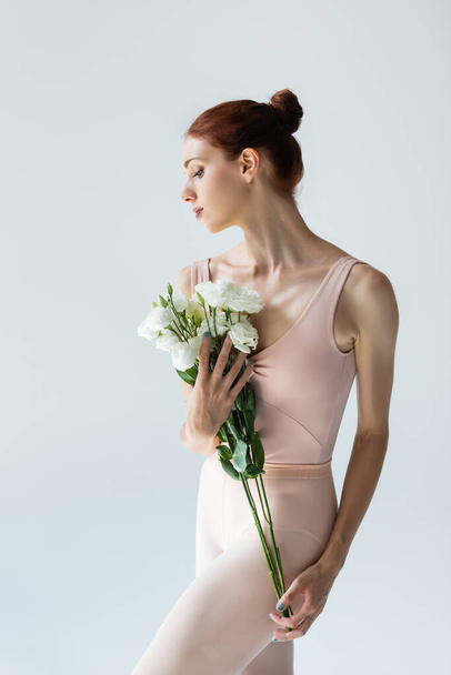 redhead ballerina holding bouquet of flowers isolated on grey - Foto, Imagen