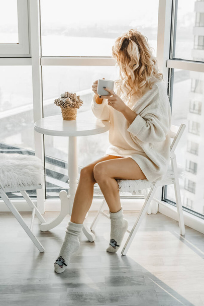 Woman is sitting and drinking coffe in light interior. - Foto, Bild