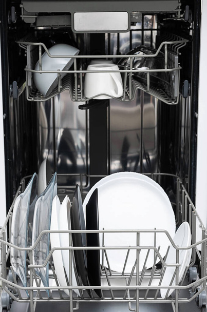 Nettoyer les assiettes après le lavage au lave-vaisselle à la maison. Cuisine moderne avec lave-vaisselle. Appareils ménagers.  - Photo, image