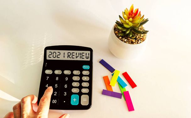 Economy and business concept. REVIEW 2021 on calculator display, with cactus, stickers isolated on white background. - Photo, Image