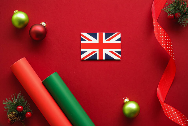 Britská vánoční tradice a koncept prázdninového designu. Union Jack vlajka Velké Británie a vánoční ozdoby a dekorace na červeném pozadí jako flatlay horní pohled - Fotografie, Obrázek