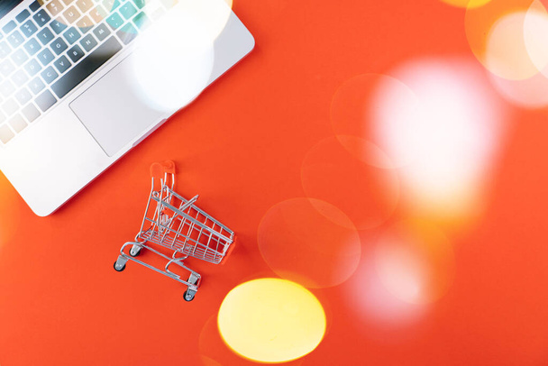Christmas online shopping on laptop with credit card. New year decorations candy canes, shopping cart and presents box top view flat lay on red background. Merry Xmas winter holidays sales concept - Photo, Image