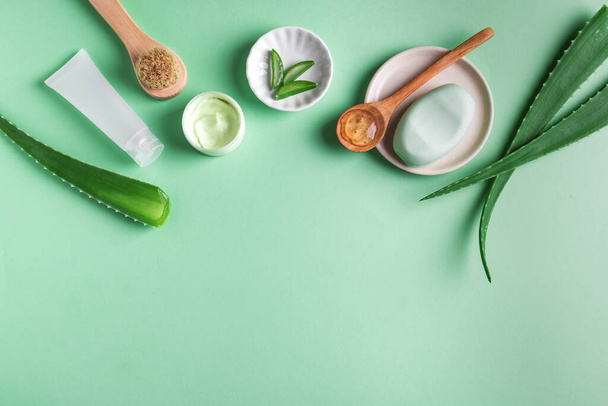 Aloe vera plant leaves, gel, skin care products on green, top view, copy space. Natural organic aloe vera cosmetics for face and body care. - 写真・画像