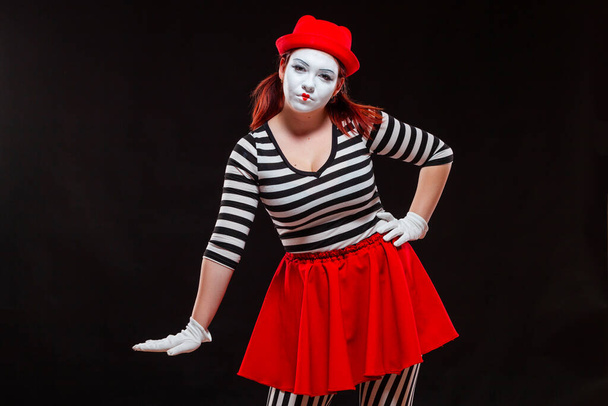 Portrait of female mime artist performing, isolated on black background. Woman is standing with her hand down. Symbol of low income, small salary, falling prices - Fotó, kép