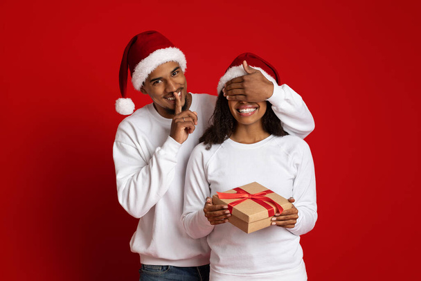 Sevgi dolu siyah adam Xmas 'a hediye veriyor kız arkadaşına, gözlerini kapatıyor. - Fotoğraf, Görsel