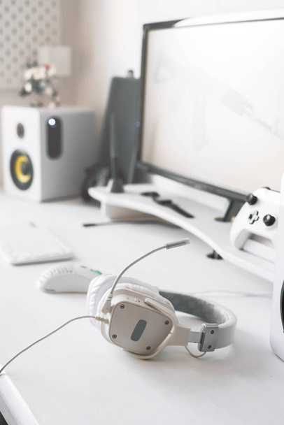 White large gaming headphones are on the table. Close-up in a bright interior - Photo, image