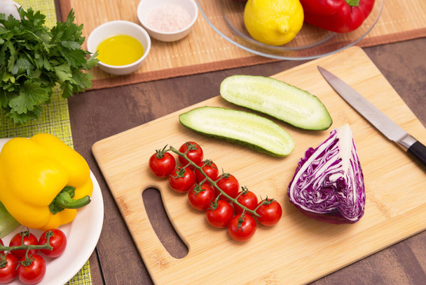 Different vegetables for cooking healthy vegetarian vegan diet food. Cutting vegetable for salad on wooden board on kitchen - Foto, Imagem