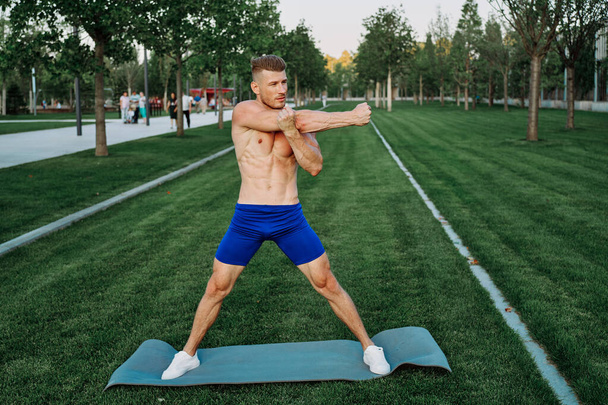 athletic man in blue shorts working out in the park - Fotoğraf, Görsel