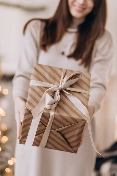 Junge Frau Porträt halten Geschenk in Weihnachtsfarbe Stil. Lächeln glückliches Mädchen auf weißem Hintergrund. - Foto, Bild