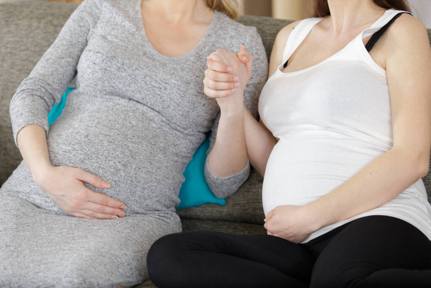 cropped view of pregnant women hand in hand on sofa - Fotografie, Obrázek