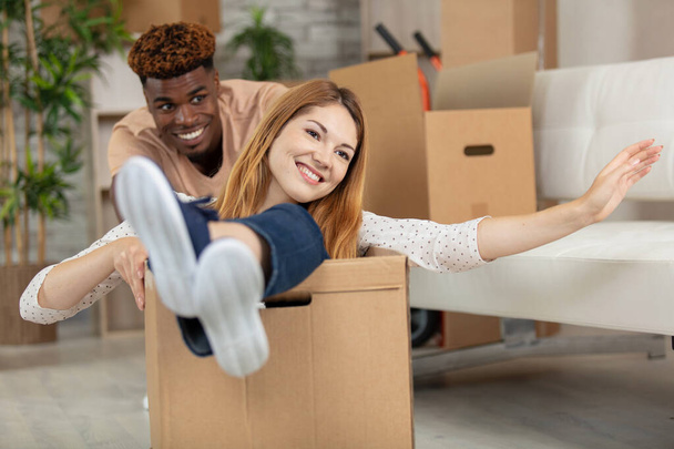 happy young man pushing woman sitting in cardboard box - Фото, зображення