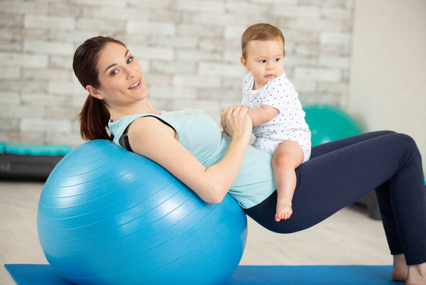 young mother does fitness exercises together with baby - Foto, afbeelding