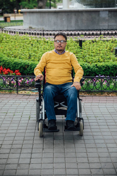 Tekerlekli sandalyeli engelli bir adam şehirde dolaşıyor. - Fotoğraf, Görsel