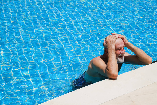 Portrait caucasian elder, senior mature man resting in swimming pool - 写真・画像