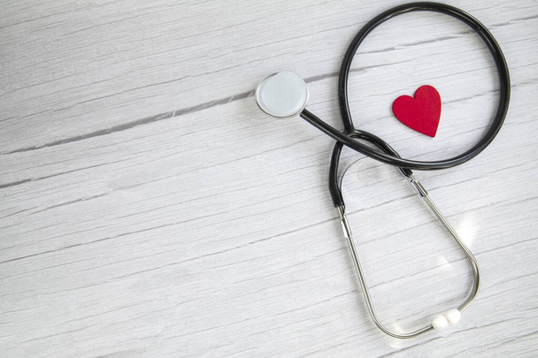 Piros szív és egy orvosi sztetoszkóp, biztosítás, kórház, világegészségügyi nap koncepció felső nézet fehér fa háttér másolás hely szöveges - Fotó, kép