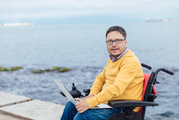 mężczyzna niepełnosprawny na wózku pracuje na laptopie zdalnie - Zdjęcie, obraz