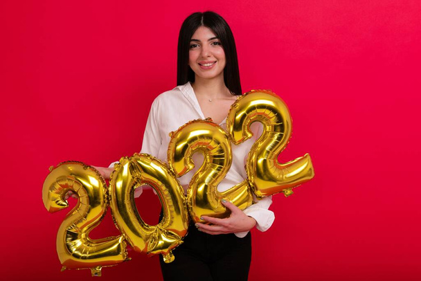 Una joven con una camisa blanca sostiene los números del próximo año nuevo 2022 - Foto, imagen