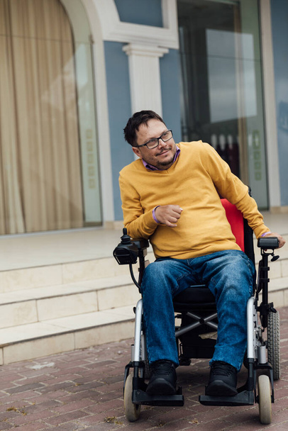 un hombre con una discapacidad en silla de ruedas en un paseo por la calle - Foto, Imagen