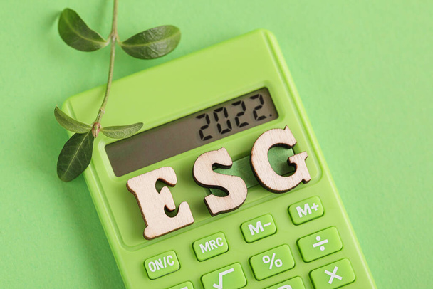 ESG. Planes para 2022 escritos en calculadora verde. Planta fresca, calculadora verde sobre fondo verde. Medio Ambiente, Social, Gobierno Corporativo. - Foto, Imagen
