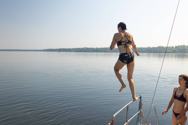 Дівчина стрибає у воду з яхти на заході сонця. відпочинь на воді. веселий час. відпустка пригоди
 - Фото, зображення